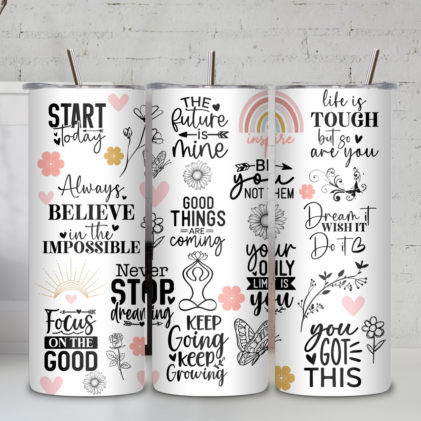 Three motivational tumblers with inspirational quotes on a white surface with a light gray brick wall background.