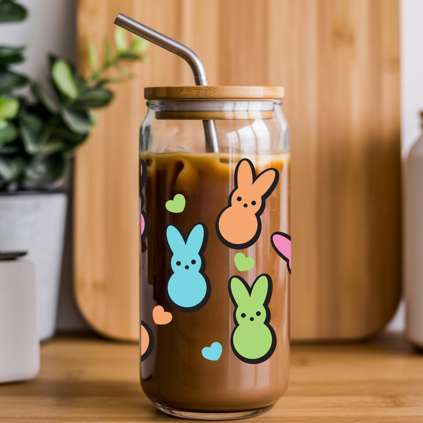 Glass tumbler with Peeps-themed stickers filled with a brown liquid on a wooden surface.